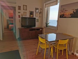 een eetkamer met een tafel en stoelen en een televisie bij Blue Nest in Genua