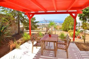 a wooden table and chairs under a red pergola at Paradisia Villas in Naxos Chora