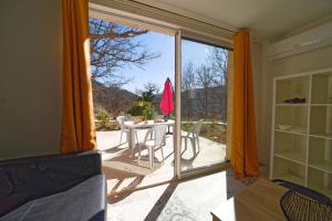 Habitación con puerta corredera de cristal, mesa y sillas. en Les quatre chênes, en Bauduen