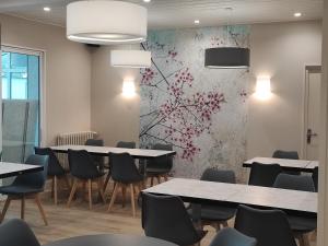 a dining room with tables and chairs and a wall with flowers at Le Relais des Primeurs LOGIS HOTEL in Taulé