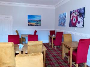 a dining room with red chairs and tables at Southbank Guesthouse in Elgin