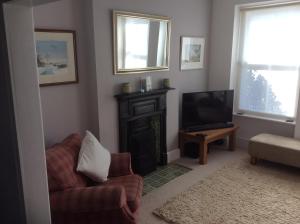 a living room with a fireplace and a chair and a television at Lovely Victorian town house close to the sea. in Bangor