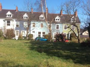 una gran casa blanca con un coche azul delante de ella en Lovely Victorian town house close to the sea. en Bangor