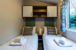 two beds in a small room with towels on them at Sea Squirrel - Norfolk Cottage Agency in Holt