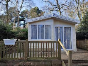 a small house on a deck with a fence at Sea Squirrel - Norfolk Cottage Agency in Holt