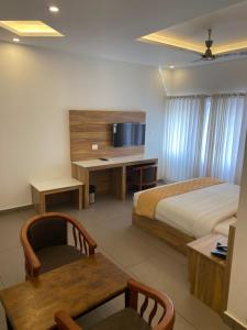 Munnar Ice Queen Resorts في مونار: غرفة في الفندق مع سرير ومكتب مع تلفزيون