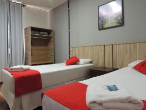 a hotel room with two beds with red accents at Hotel Gontijo Belo Horizonte - Próximo a Rodoviária e Praça Sete in Belo Horizonte