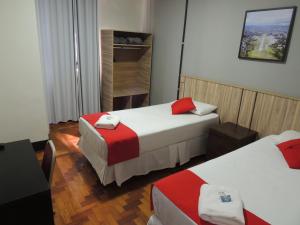 a hotel room with two beds with red and white sheets at Hotel Gontijo Belo Horizonte - Próximo a Rodoviária e Praça Sete in Belo Horizonte