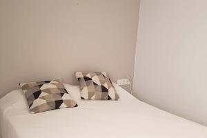 Una cama blanca con dos almohadas encima. en Casa cómoda y equipada para 6 en centro pueblo, en Torroella de Montgrí