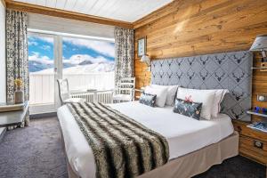 a bedroom with a bed and a large window at Hôtel les Campanules by Les Etincelles in Tignes
