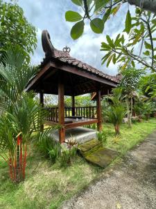 a wooden gazebo with a bench in the grass at Ndalem Setumbu in Magelang