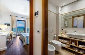 a bathroom with a tub and a sink and a bed at Hotel Dei Pini in Alghero