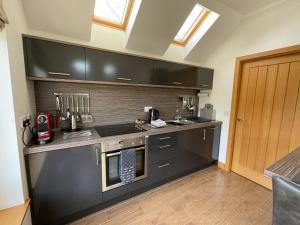 a kitchen with black cabinets and a stove top oven at The Annexe at Rauldon in Inverness