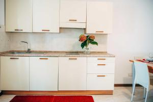 a kitchen with white cabinets and a vase of flowers at Camping Wien in Peschiera del Garda