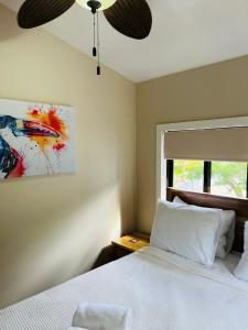 a bedroom with a white bed with a ceiling fan at The Flying Toucan in Placencia Village
