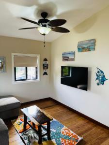 a living room with a ceiling fan and a table at The Flying Toucan in Placencia Village