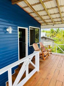 a blue house with two chairs and a table on a deck at The Flying Toucan in Placencia