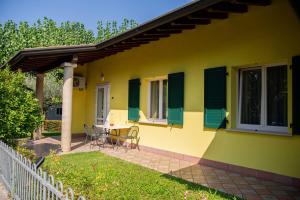 a yellow house with green shutters and a table and chairs at Camping Wien in Peschiera del Garda
