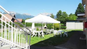 une tente blanche avec des tables et des chaises blanches sur l'herbe dans l'établissement Le Conty, à Saint-Jorioz