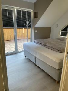 a bedroom with a bed and a large window at Praktfull hytte til utleie egnet for barnefamilier in Søgne