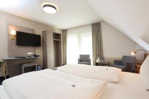 ein Hotelzimmer mit 2 Betten und einem Flachbild-TV in der Unterkunft Hotel Zur Linde in Neddenaverbergen