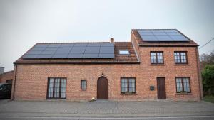 una casa de ladrillo con paneles solares en el techo en De Strikker, en Balen