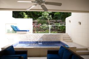 Luxury 3-Bed Villa St James near Beach & Gym في سانت جيمس: مسبح والكراسي الزرقاء ومروحة السقف