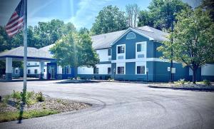 Best Western Brockport Inn & Suites في Brockport: البيت الأزرق والأبيض مع العلم الأمريكي