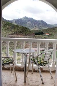 einen Tisch und Stühle auf einem Balkon mit Bergblick in der Unterkunft Brisas de Anaga in Santa Cruz de Tenerife