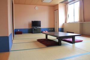 a living room with a table and a tv at Osaka International Youth Hostel in Takaishi