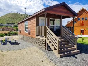 a log cabin with a deck and a table at Castle Gate RV Park in Helper