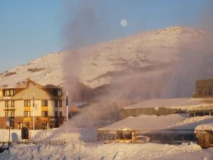 a building in the snow with a mountain in the background at Perisher Manor Hotel in Perisher Valley