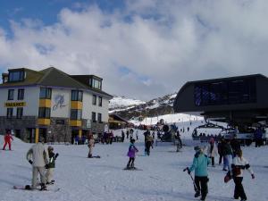 un groupe de personnes skier dans la neige près d'un lodge de ski dans l'établissement Perisher Manor Hotel, à Perisher Valley