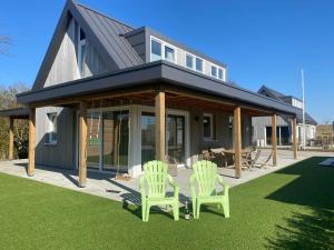 two green lawn chairs sitting in front of a house at luxe Villa Maroma Regal aan Veerse meer met 4 Ebikes GasBBQ & EV laadpaal in Kamperland