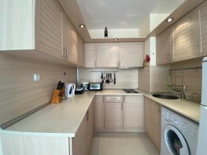cocina con armarios de madera, lavadora y secadora en BLUE MARINE C16 Apartment Sunny Beach en Sunny Beach