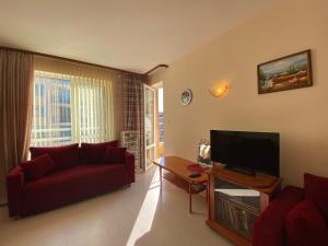 a living room with a red couch and a television at BLUE MARINE C16 Apartment Sunny Beach in Sunny Beach