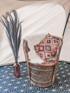 a wicker chair with a pillow next to a plant at Immaculate Lotus Belle Tent Retreat North Devon in Bideford