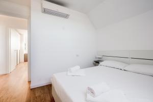 Biała sypialnia z białym łóżkiem i białą ścianą w obiekcie Modern APT with Terrace, WIFI & AC w Mediolanie