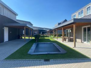 een tuin met een zwembad in het midden van een gebouw bij luxe Villa Maroma Mistral aan Veerse meer met 4 Ebikes GasBBQ & EV laadpaal in Kamperland