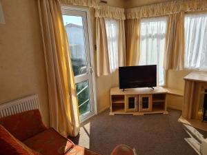 a living room with a flat screen tv in front of a window at 6 Berth central heated The Grange (Balmoral II) in Ingoldmells