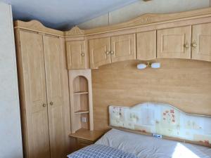 a bedroom with wooden cabinets and a bed at 6 Berth central heated The Grange (Balmoral II) in Ingoldmells