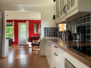 uma cozinha com armários brancos e uma parede vermelha em Nyhyttan Nora Bergslagen The Three Birches em Nora