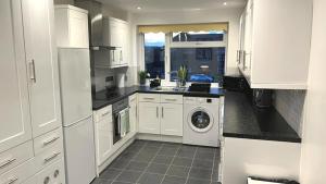 a kitchen with white cabinets and a washer and dryer at FW Haute Apartments at Stanmore, 3 Bedrooms and 1 Bathroom with additional WC, Single or Double Beds, Pet-Friendly Flat with FREE WIFI and PARKING in Stanmore