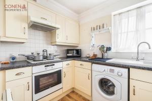cocina con armarios blancos, lavadora y secadora en Stunning 2-Bed Apartment in Grays, en West Thurrock