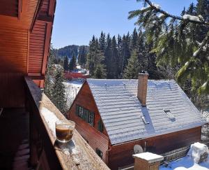 a house in the snow with a drink on a balcony at Karak Apartman in Harghita-Băi