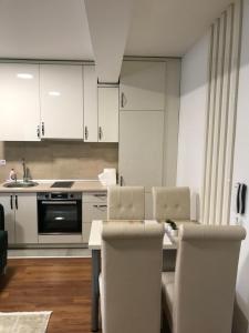 a kitchen with white cabinets and a table and chairs at Green Apartment in Novi Pazar