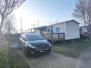 a black car parked in front of a house at Assist' Mobil home 363 - Charmant mobil home 8 personnes 3 chambres in Onzain