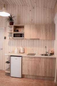 uma cozinha com armários de madeira, um lavatório e um micro-ondas em Sila terases em Madona