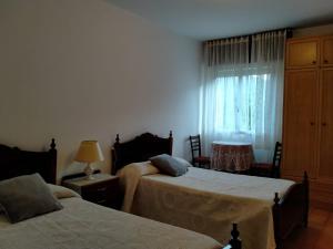 a bedroom with two beds and a window at Casa da Fontiña in Seoane