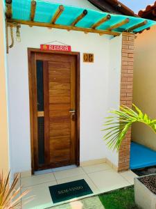 a house with a wooden door with a sign on it at FLATS VILLAS LITORAL SUL - Lagoa do Pau - Coruripe - AL in Coruripe